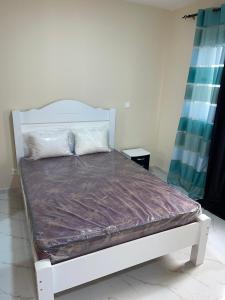 Cama blanca en una habitación con colchón visor en madison place en Praia