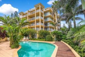 an apartment building with a swimming pool and palm trees at Orion Unit 4 in Gold Coast