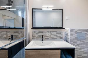 Très Bel Appartement Spacieux et Central في شوليه: حمام مع حوض أبيض ومرآة