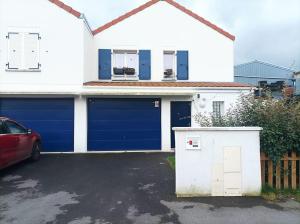 uma casa branca com portas de garagem azuis e um carro vermelho em Résidence Juan Valera em Vaujours