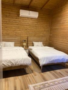 2 camas en una habitación con paredes de madera en اكواخ همسي كوي, en Tabuk
