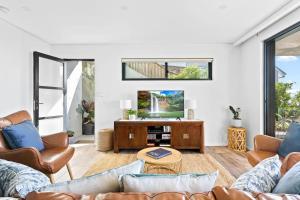 a living room with a couch and a tv at Ocean Views, Deck and Parking at Beach Apartment in Collaroy