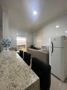 eine Küche mit einem großen Tisch mit Stühlen und einem Kühlschrank in der Unterkunft Apartamento Completo - Algarve 203 e 204 in Patos de Minas