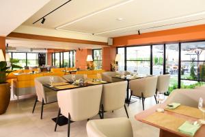 un restaurant avec des tables, des chaises et des fenêtres dans l'établissement Floral Court Hotel & Residence Sukhumvit 13, à Bangkok