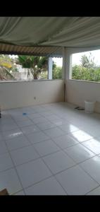 a room with a white tiled floor with two windows at RECANTO DO SOL SABIAGUABA CEARA in Fortaleza
