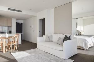 a white living room with a white couch and a bed at Nalu in Newcastle