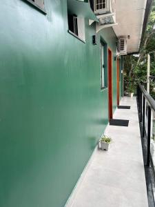 a building with a green wall and a hallway at Morada do Sol Suítes in Arraial do Cabo