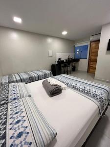 two twin beds in a room with a table at Morada do Sol Suítes in Arraial do Cabo