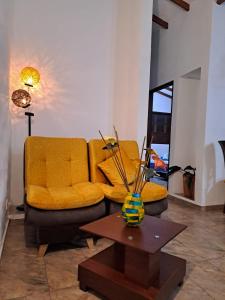 a living room with a yellow couch and a table at Apartahotel Sacrosanta Trinidad in Villa de Leyva