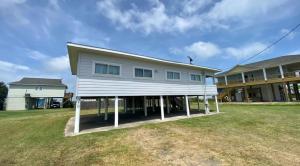 a white house on a lawn in front of a house at Sandy Haven in Bolivar Peninsula