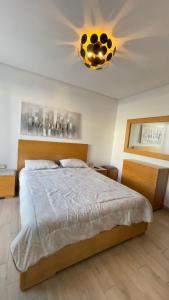 a bedroom with a large bed with a ceiling at Appartement Prestigia des nations in Salé