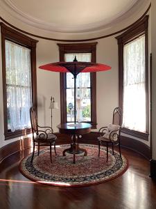 クインシーにあるHistoric Queen Anne Mansionのテーブル、椅子2脚、パラソルが備わる客室です。