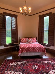 a bedroom with a bed with a red blanket and windows at Historic Queen Anne Mansion in Quincy