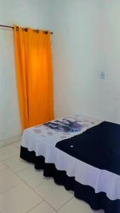 a bed in a room with a orange curtain at Kitnet no Centro de São Pedro da Aldeia De frente para Lagoa in São Pedro da Aldeia