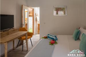 a living room with a table and a tv and a bed at Matira Beach House in Bora Bora