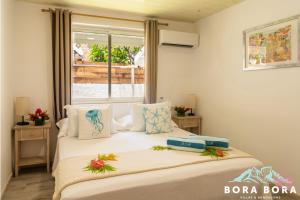 two beds in a room with a window at Matira Beach House in Bora Bora