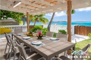 a dining table under a pergola with the ocean in the background at Matira Beach House in Bora Bora