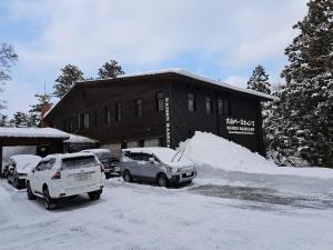 parking pokryty śniegiem przed budynkiem w obiekcie 大山ベースキャンプ（Daisen Basecamp） w mieście Daisen