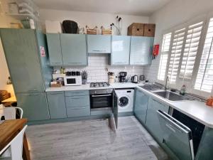 a kitchen with blue cabinets and a dishwasher at 4bed/3bath 8min to London Bridge in London