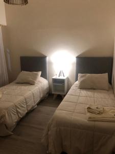 um quarto com duas camas e uma luz na parede em Un departamento con historia em Buenos Aires