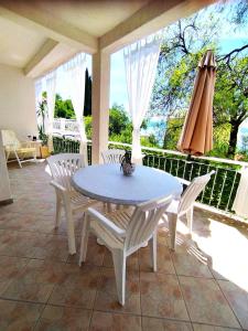 einen Tisch und Stühle auf einer Veranda mit Sonnenschirm in der Unterkunft Apartments by the sea Zivogosce - Porat, Makarska - 6807 in Igrane + 31 Fotos