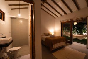 een slaapkamer met een bed en een badkamer met een wastafel bij Casa Vivá in Arraial d'Ajuda