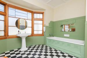 a green bathroom with a tub and a sink at Art Deco Charm - Amazing River Views Inner City in Gisborne