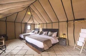 Merzouga Luxury Traditional Camp في مرزوقة: غرفة نوم بسريرين في خيمة