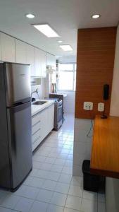 a kitchen with a stainless steel refrigerator and white cabinets at Ap na Barra da Tijuca, atrás do Windsor in Rio de Janeiro