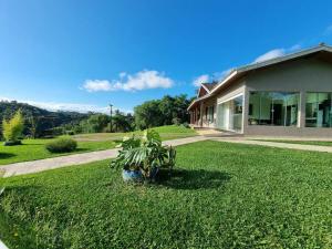 ein Haus mit einem grünen Hof mit einer Pflanze in der Unterkunft Casa de campo perfeita para suas férias! in Quatro Barras