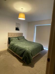 a bedroom with a bed with a green comforter at Room in Modern Luxury 3 bed Apartment in City Center in Birmingham