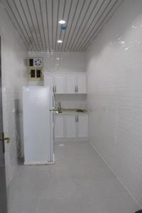 - une cuisine blanche avec un réfrigérateur dans l'établissement بارك فيو للوحدات السكنية, à Birzayn