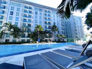 a swimming pool with chairs and a building at Pattaya City Center Residence K in Pattaya Central