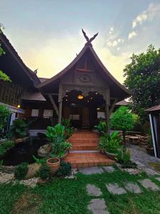 a building with a triangular roof with stairs in a yard at Malulee Homestay/Cafe/Massage in Lampang