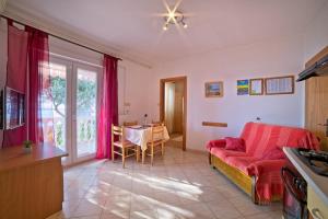 a living room with a red couch and a table at Apartments with parking space Supetarska Draga - Gonar, Rab - 22586 in Rab