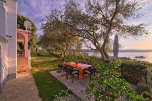 a table and chairs on a patio with a view of the water at Apartments with parking space Supetarska Draga - Gonar, Rab - 22586 in Rab