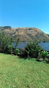 un campo de hierba con un cuerpo de agua y una montaña en Jardín Paraíso, en Amatitlán