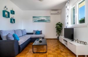 a living room with a blue couch and a tv at Family friendly house with a swimming pool Primorski Dolac, Zagora - 22653 in Primorski Dolac