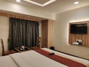 a hotel room with a bed and a flat screen tv at Hotel Shelter Palace in Navi Mumbai
