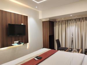 a hotel room with a bed and a tv on the wall at Hotel Shelter Palace in Navi Mumbai