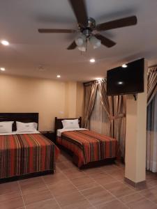 1 dormitorio con 2 camas y ventilador de techo en BRISAS DE LA BAHIA HOTEL, en Paracas