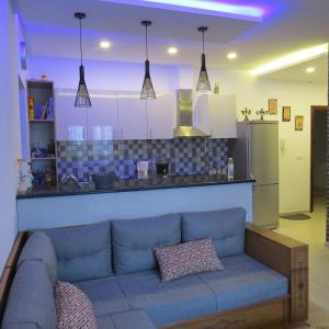 Appartement moderne, vue mer في هرقلة: غرفة معيشة مع أريكة زرقاء ومطبخ
