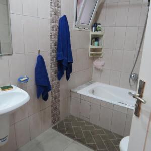 ein Badezimmer mit einer Badewanne und einem Waschbecken in der Unterkunft Appartement moderne, vue mer in Harqalah