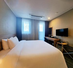 a hotel room with a large white bed and a desk at Hotel K-Tree Pyeongtaek in Pyeongtaek