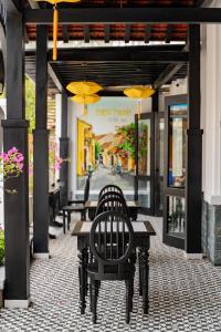 eine Terrasse mit Tischen, Stühlen und Sonnenschirmen in der Unterkunft Thien Thanh Central Boutique Hotel by Minova in Hoi An