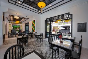 a restaurant with tables and chairs in a room at Thien Thanh Central Boutique Hotel by Minova in Hoi An