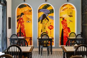 會安的住宿－Thien Thanh Central Boutique Hotel by Minova，餐厅设有桌椅,墙上挂有绘画作品