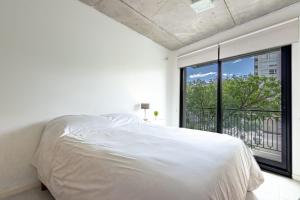 a bedroom with a white bed and a large window at Elegancia y Confort en el Corazón de San Telmo in Buenos Aires