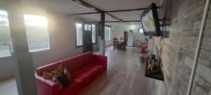 a living room with a red couch and a flat screen tv at Casona Los Coihues in Tolhuin