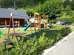 um parque infantil num pátio ao lado de um edifício em Camping Prado Verde em Vilamós